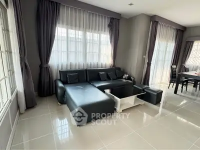 Spacious living room with modern black leather sofa and elegant dining area