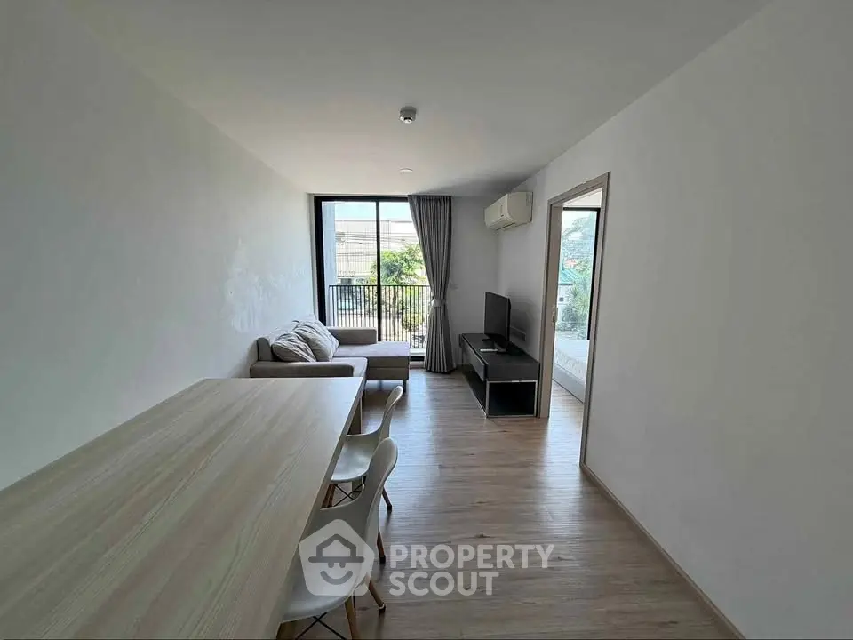 Modern living room with sleek furniture and natural light, featuring a cozy sofa and dining area.