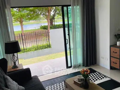 Charming living room with sliding glass doors opening to a serene garden view, perfect for relaxation.