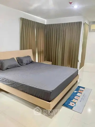 Spacious bedroom with modern decor and large windows in a stylish apartment.