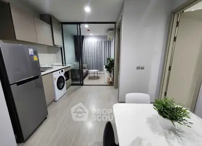 Modern kitchen with sleek appliances and open layout leading to a cozy living area.