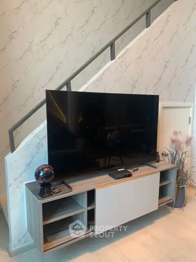 Modern living room with sleek TV stand and stylish decor under a staircase.