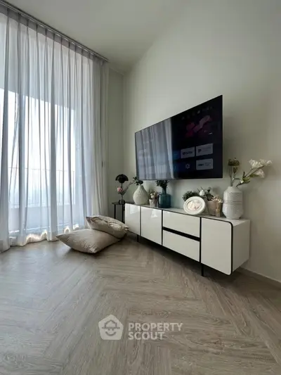 Modern living room with sleek TV setup and elegant decor, featuring floor-to-ceiling windows and stylish flooring.