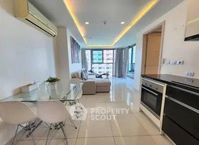 Modern open-plan living room with dining area and kitchen, featuring sleek design and natural light.