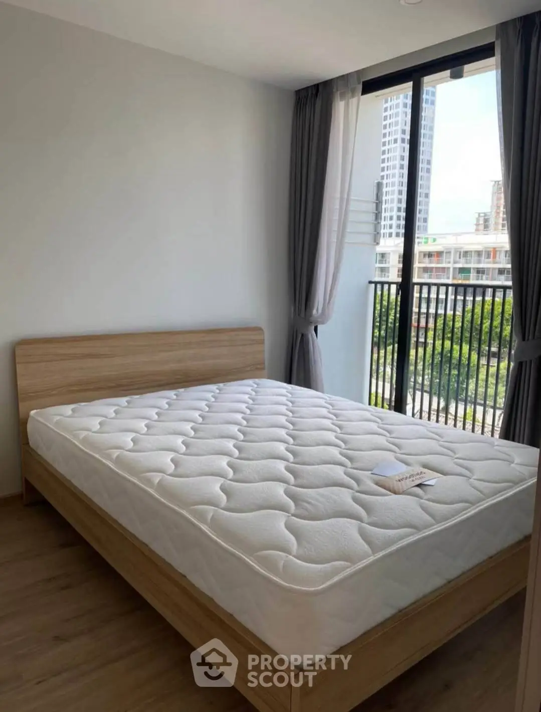 Modern bedroom with large window and city view, featuring a comfortable bed and stylish decor.