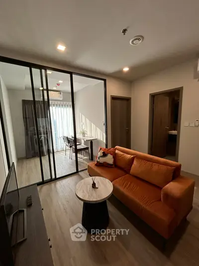 Modern living room with glass partition and stylish orange sofa in a contemporary apartment.