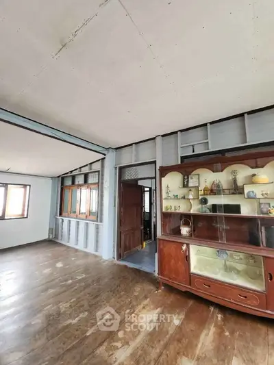 Spacious vintage living room with wooden floors and classic display cabinet.