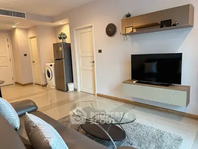 Modern living room with sleek furniture and appliances, featuring a washing machine and flat-screen TV.