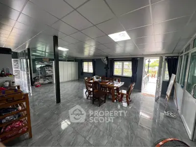 Spacious open-plan living area with dining set and large windows, leading to a balcony.