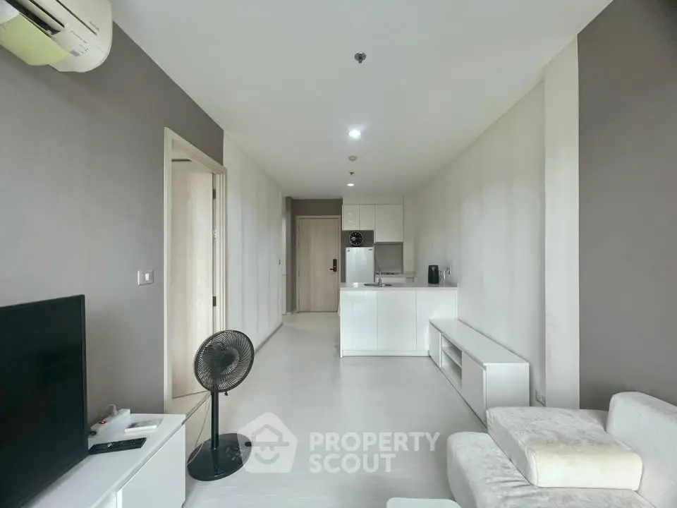 Modern minimalist living room with open kitchen layout and sleek white furniture.