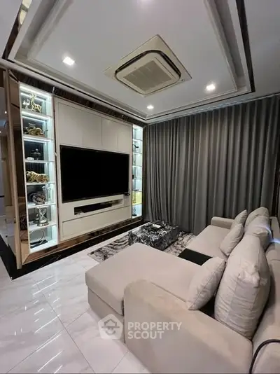 Luxurious living room with modern decor and large TV, featuring elegant lighting and plush seating.
