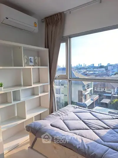 Bright bedroom with large window offering stunning city view and modern shelving unit.