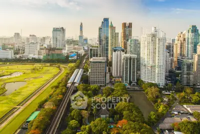 Stunning aerial view of modern city skyline with lush green park and golf course, perfect urban living.
