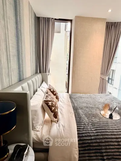 Luxurious bedroom with elegant decor and large window offering natural light.