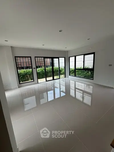 Spacious modern living room with large windows and glossy tiled floor