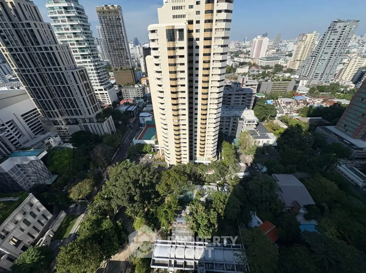Stunning aerial view of urban high-rise buildings with lush greenery and cityscape backdrop.