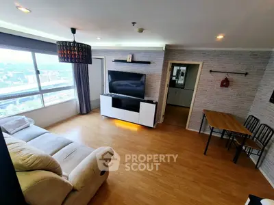 Spacious living room with modern decor and city view, featuring a cozy sofa and entertainment center.