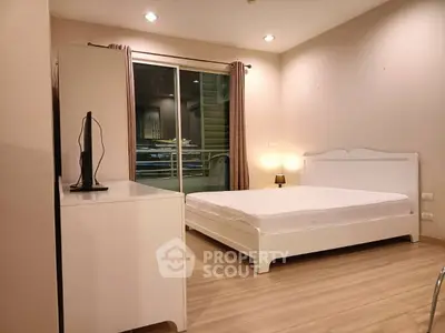 Spacious bedroom with modern decor and balcony access in a stylish apartment.