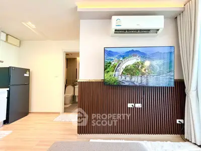 Modern living room with wall-mounted TV and air conditioning, featuring sleek design and natural light.