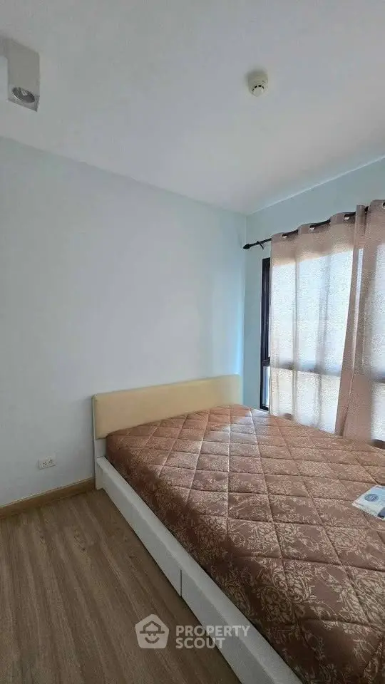 Cozy bedroom with natural light and minimalist design, featuring a comfortable bed and wooden flooring.