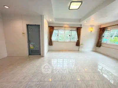 Spacious living room with large windows and tiled flooring, perfect for natural light lovers.