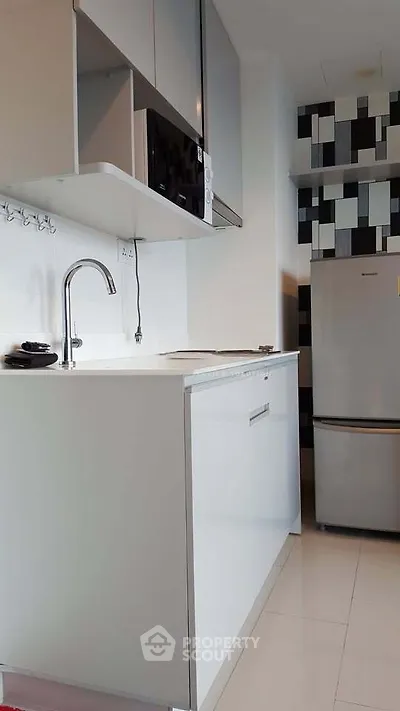 Modern kitchen with sleek white cabinetry and stainless steel appliances in a contemporary apartment.