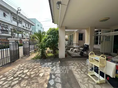 Charming residential entrance with lush greenery and spacious outdoor area, perfect for relaxation and gatherings.