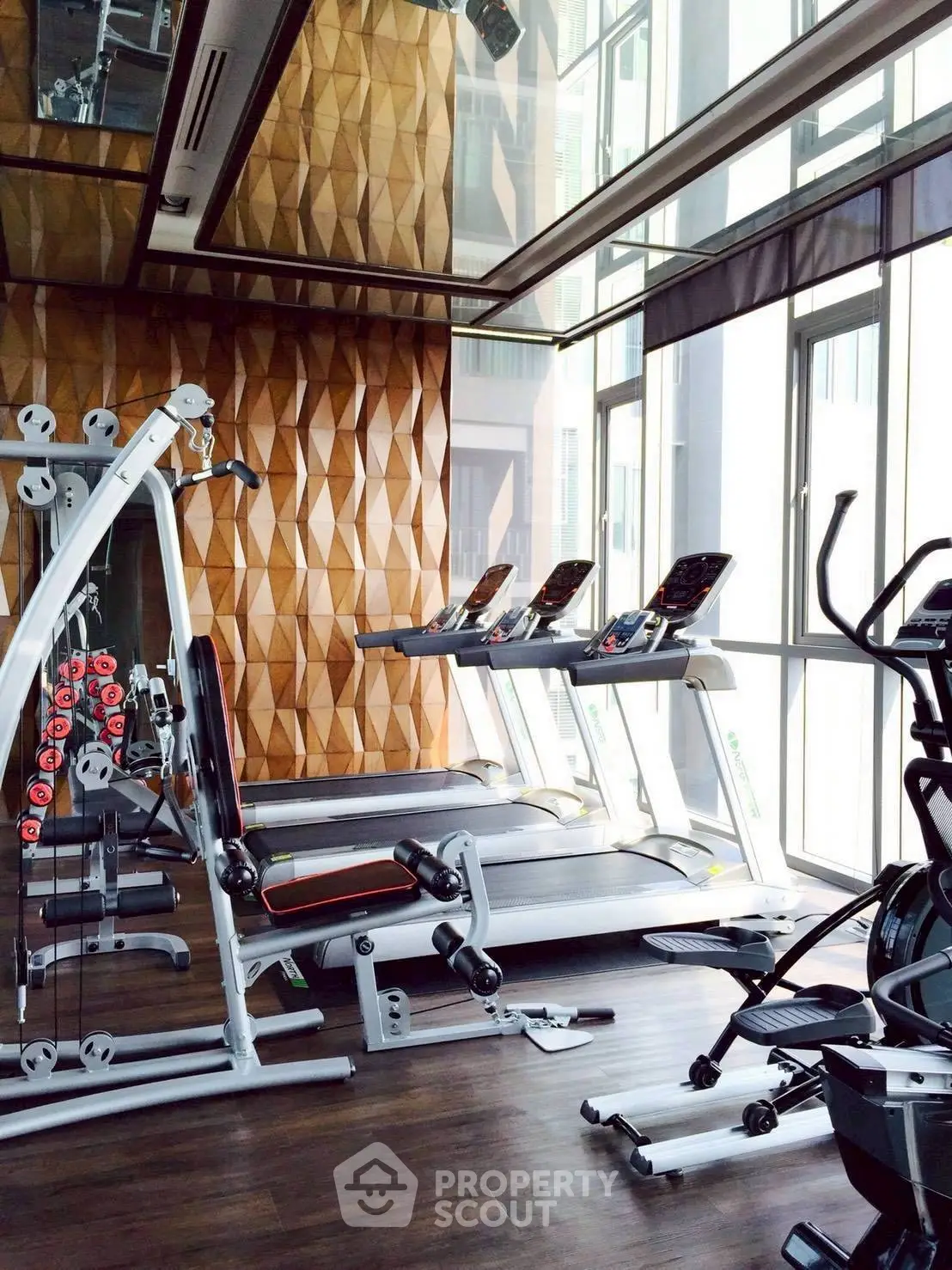 Luxurious gym with modern equipment and stylish wooden paneling in a high-end residential building.