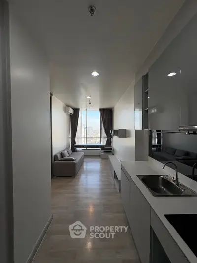 Modern apartment interior with sleek kitchen and cozy living area, featuring large windows with city view.