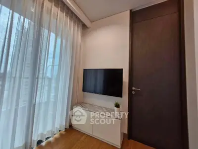 Modern living room with TV, large window, and elegant curtains in a stylish apartment.