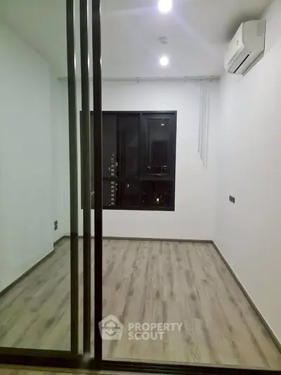 Modern empty room with wooden flooring and air conditioning, ideal for customization.