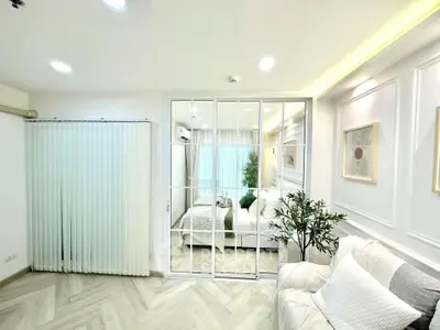Modern living room with elegant decor and mirrored sliding doors leading to a cozy bedroom.