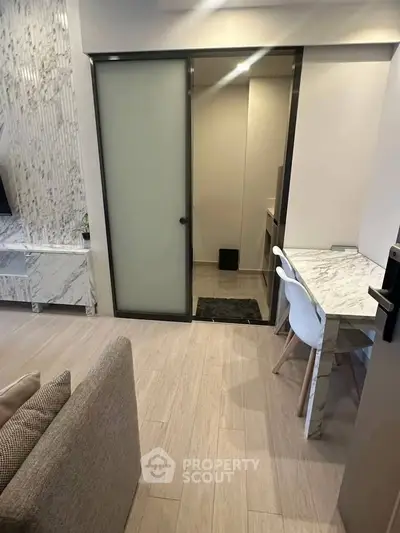 Modern living room with marble accents and sliding door to a compact study area.