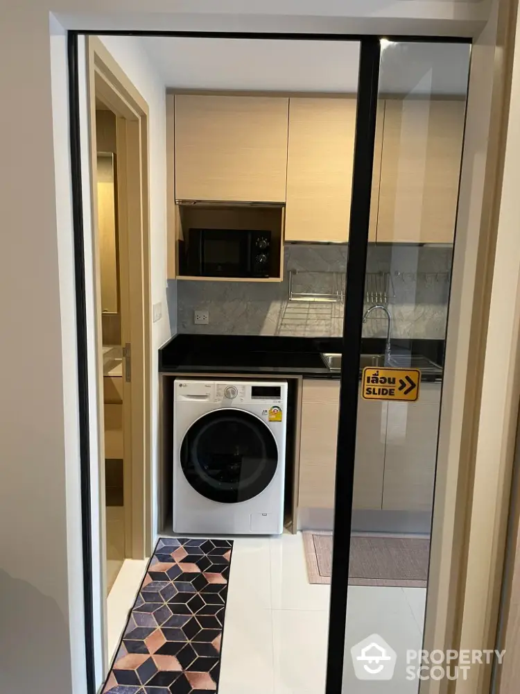 Modern compact kitchen with washing machine and microwave in sleek apartment