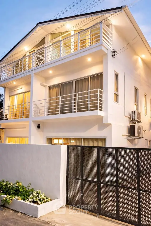 Modern three-story white house with balconies and ambient lighting