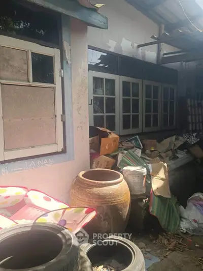 Exterior view of cluttered property with potential for renovation.