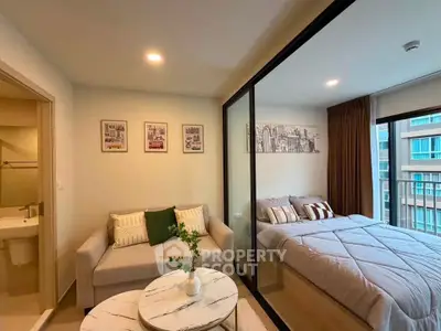 Modern studio apartment with cozy living area and bedroom separated by glass partition.