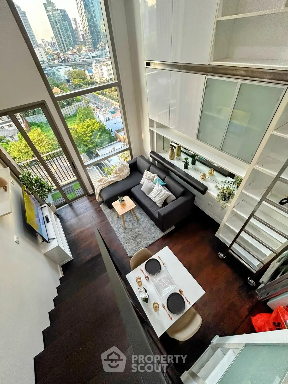 Stunning loft apartment with floor-to-ceiling windows and city view, featuring modern decor and open living space.