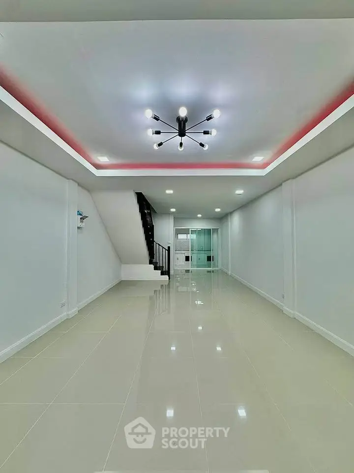 Spacious modern interior with sleek lighting and glossy tiled floors, ideal for versatile living space.