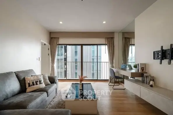 Modern living room with sleek furniture and large windows offering city views.