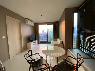 Modern living room with city view, stylish furniture, and natural light in a high-rise apartment.