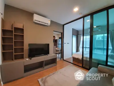 Modern apartment interior with open living room and bedroom, featuring sleek furniture and large windows.