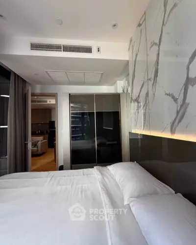 Luxurious bedroom with modern design and marble accent wall in upscale apartment.