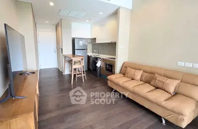 Modern living room with open kitchen, featuring sleek appliances and cozy seating area.