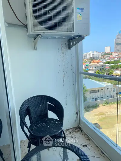 Cozy balcony with city view and air conditioning unit, perfect for relaxation.