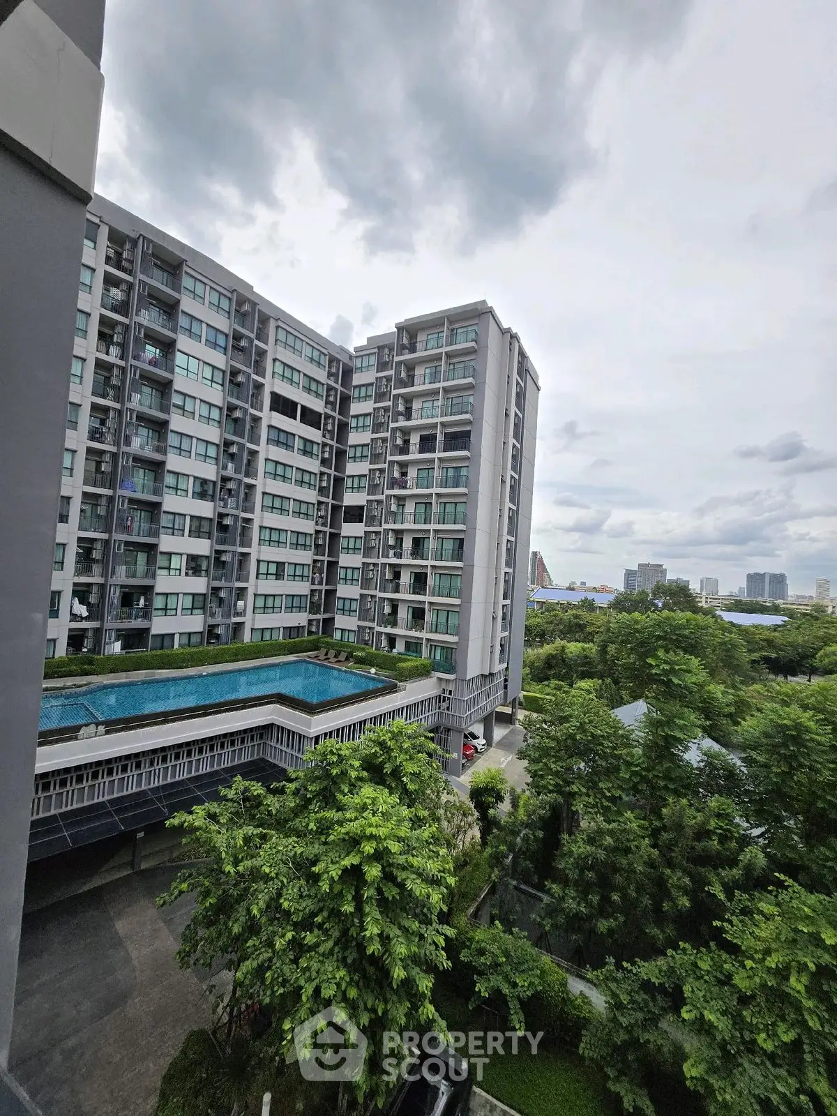 Modern high-rise building with lush greenery and pool view, ideal urban living.
