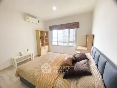 Cozy bedroom with modern furnishings and large window offering natural light.