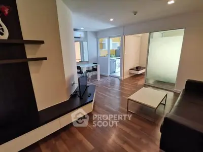 Modern living room with sleek furniture and wooden flooring, featuring an open layout and natural light.