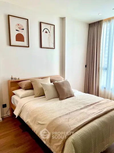 Cozy bedroom with modern decor and natural light, featuring elegant artwork and plush bedding.