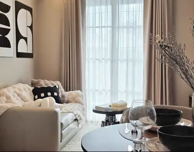 Elegant living room with cozy sofa, modern decor, and natural light through large window.